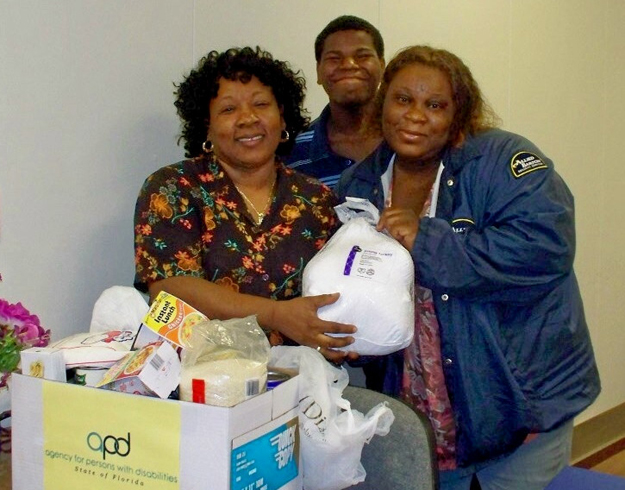 APD Area 10 employee Pauline Currie, left, presents Ronaldo Adain and his mother, Yvonne Louis, with everything they need for Thanksgiving dinnerand then some!